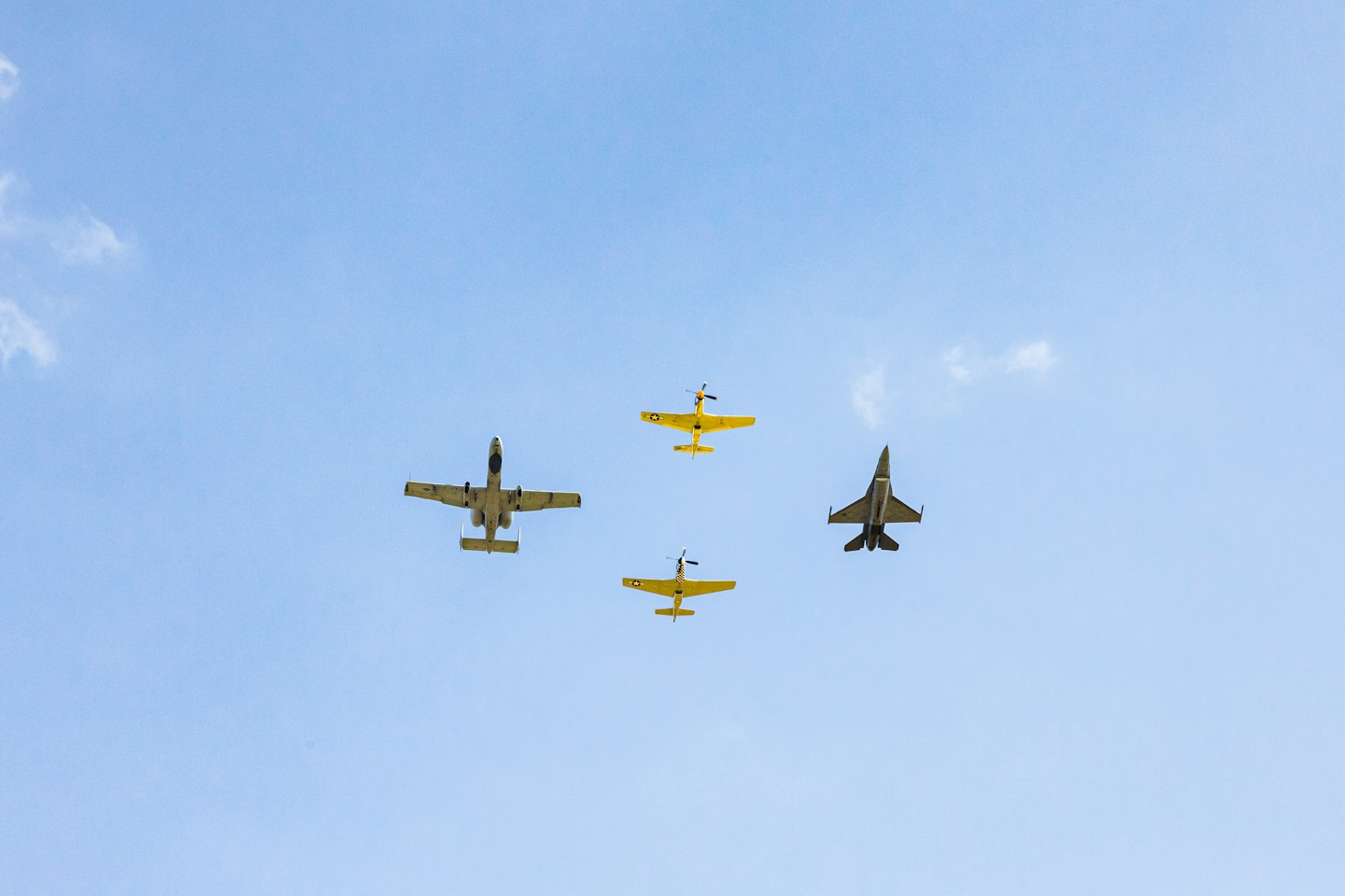 Four planes fly in formation in a blue sky.