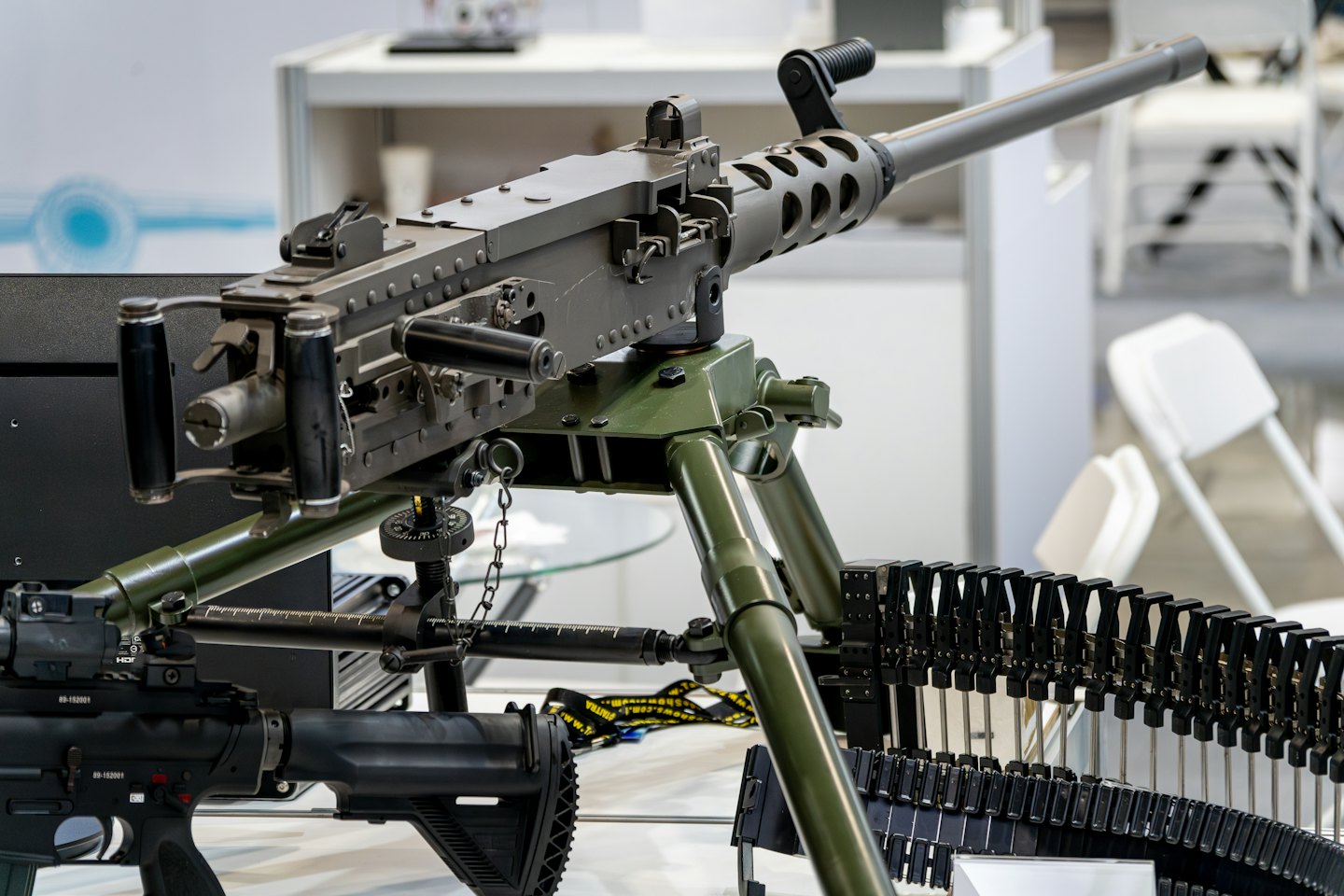 Machine gun and ammunition displayed on a tripod at an exhibition.