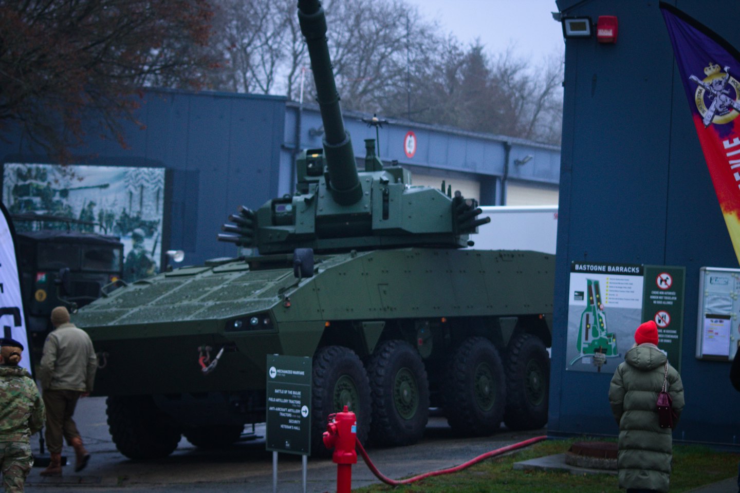 People view a large green armored vehicle at an outdoor exhibition.